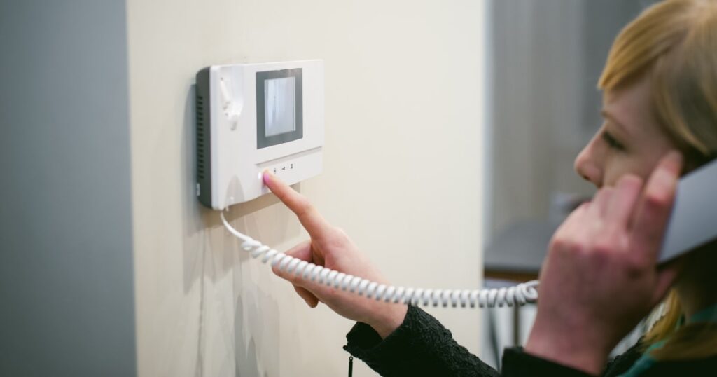 Woman answering gate intercom in her home.