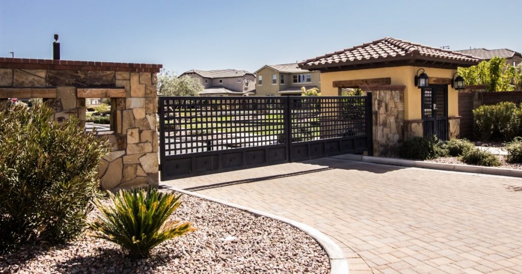 An image of a closed automatic gate with stone pillars on either side, suggesting the role of gate intercoms in enhancing security in residential areas.
